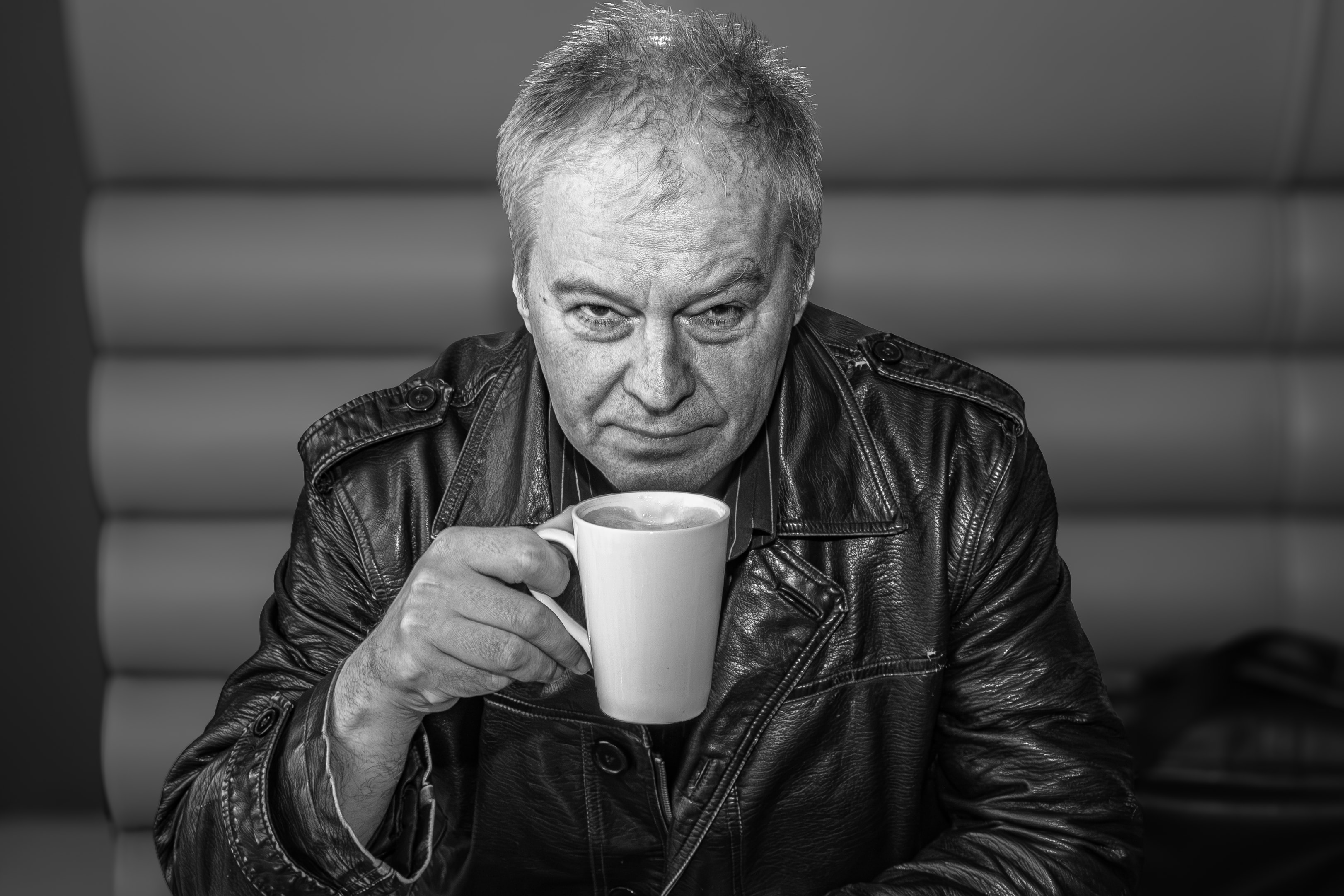 Steve Daggett of Lindisfarne in a black-and-white portrait holding a cup