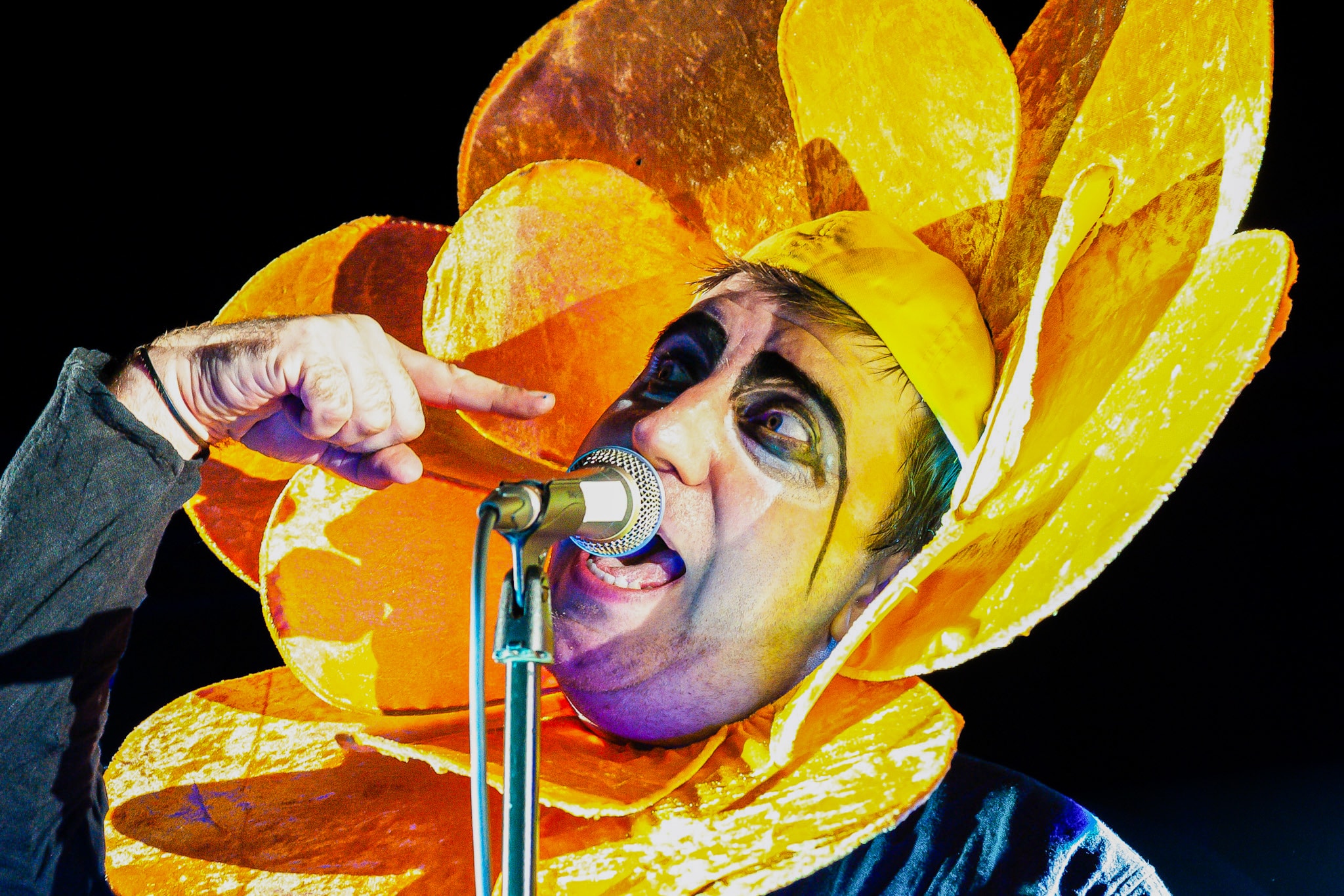Tony Patterson of RetroGenesis singing into a microphone in a bright yellow and orange flower costume