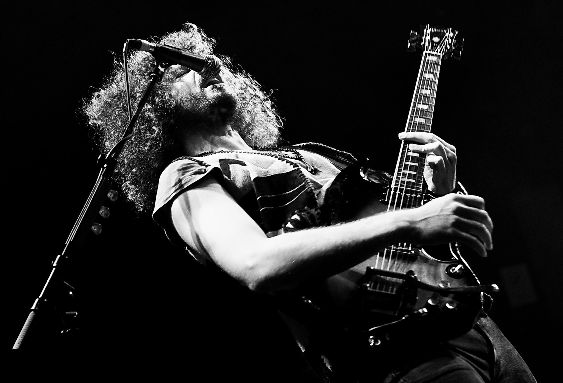 Andrew Stockdale of Wolfmother singing and playing electric guitar live in black and white