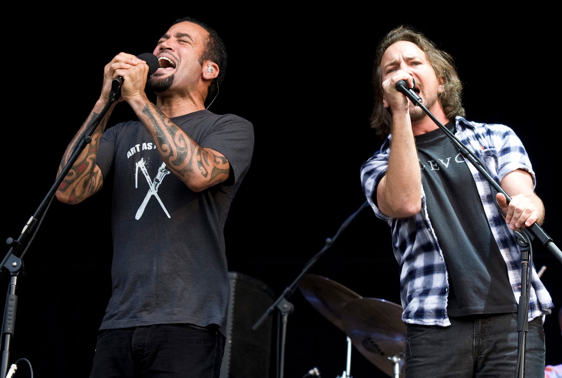 Ben Harper and Eddie Vedder singing together at microphones on an outdoor stage