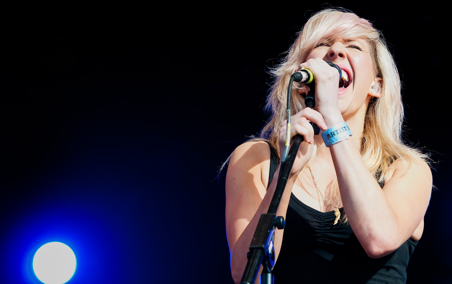 Ellie Goulding singing into a microphone during a live concert performance