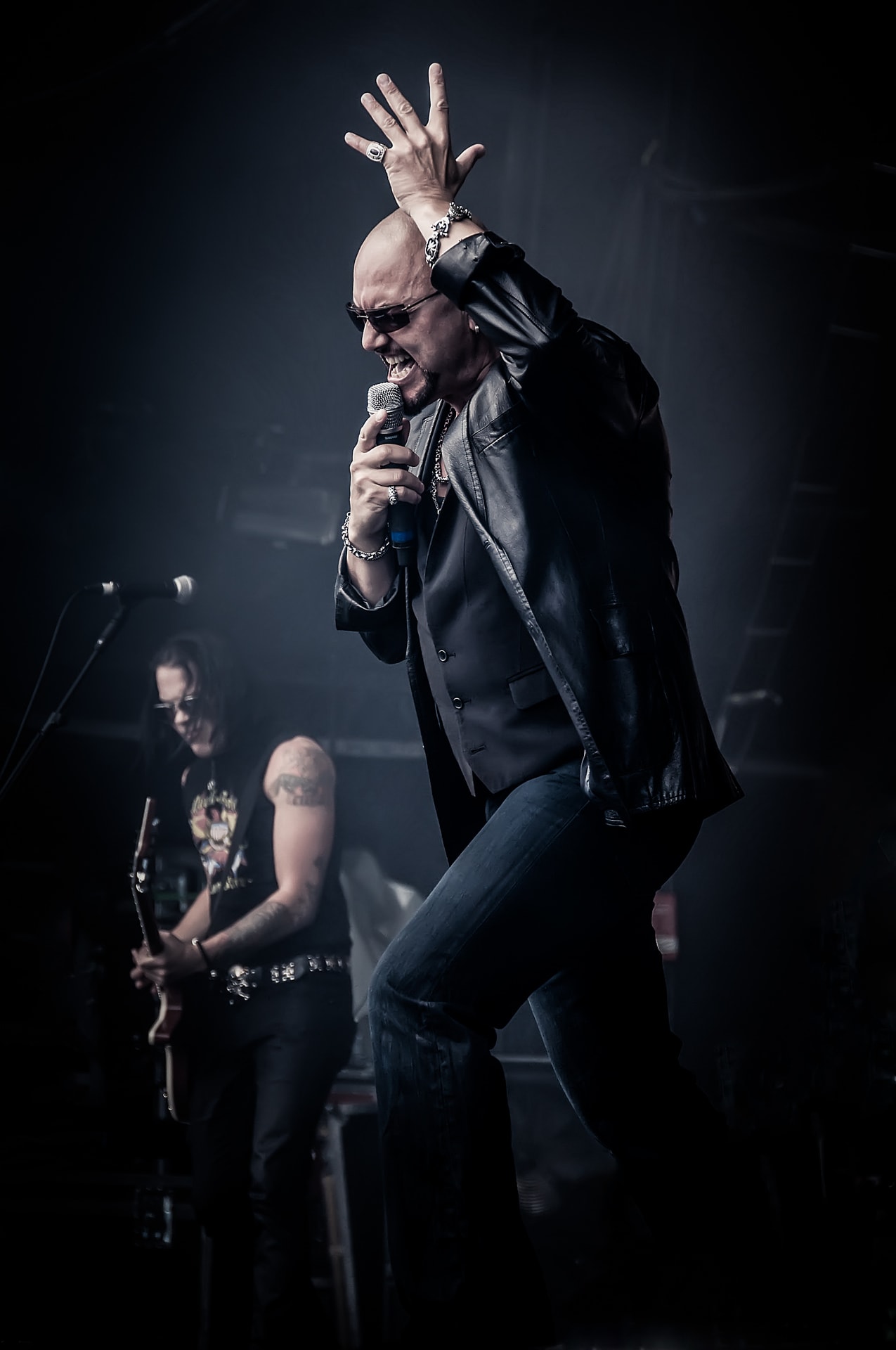 Geoff Tate of Queensrÿche singing into a microphone during a live concert