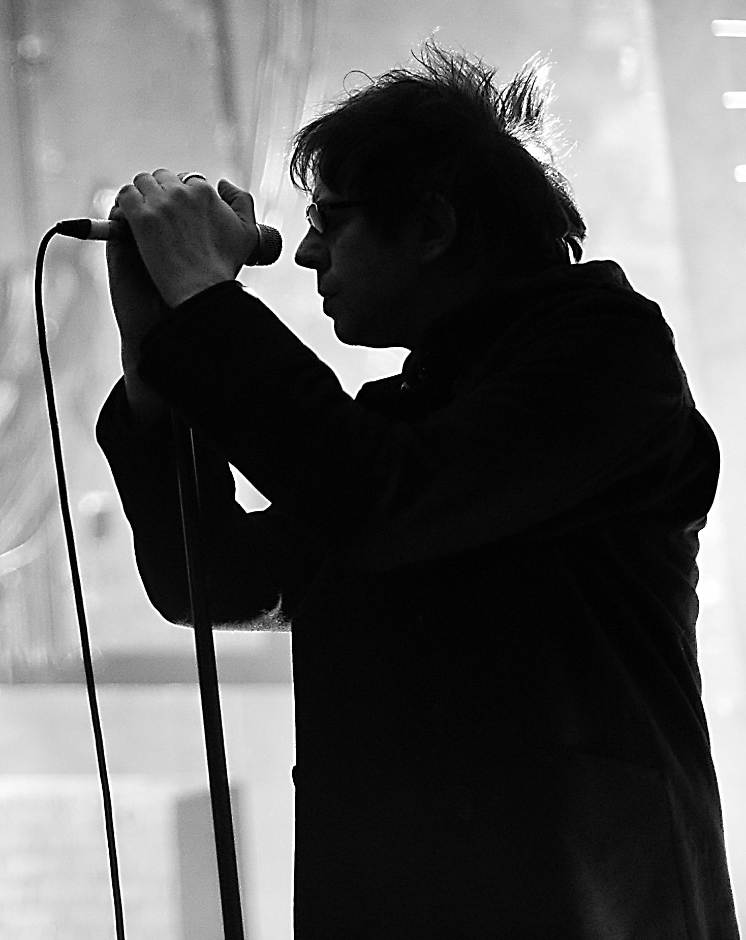 Ian McCulloch of Echo and The Bunnymen singing into a microphone in a black-and-white stage silhouette