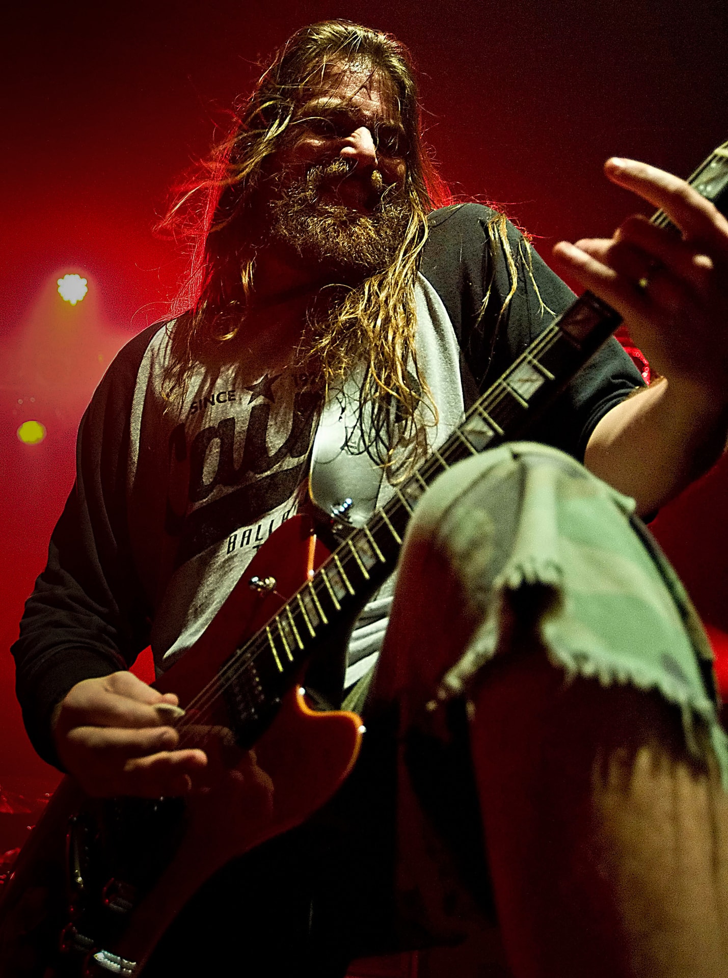 Mark Morton of Lamb of God performing live with an electric guitar under red stage lighting