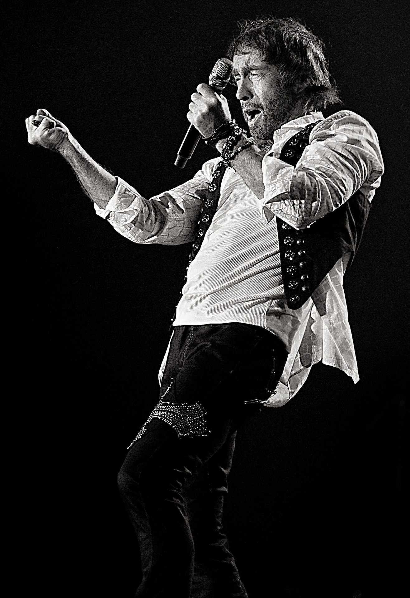 Paul Rodgers singing into a microphone in a black-and-white live performance portrait