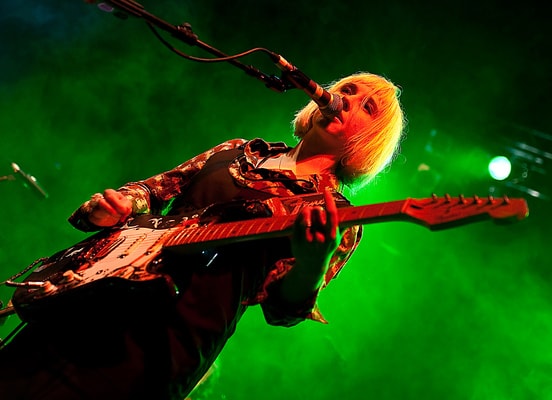 Rhiannon Ritzy Bryan of The Joy Formidable singing and playing guitar under green stage lighting