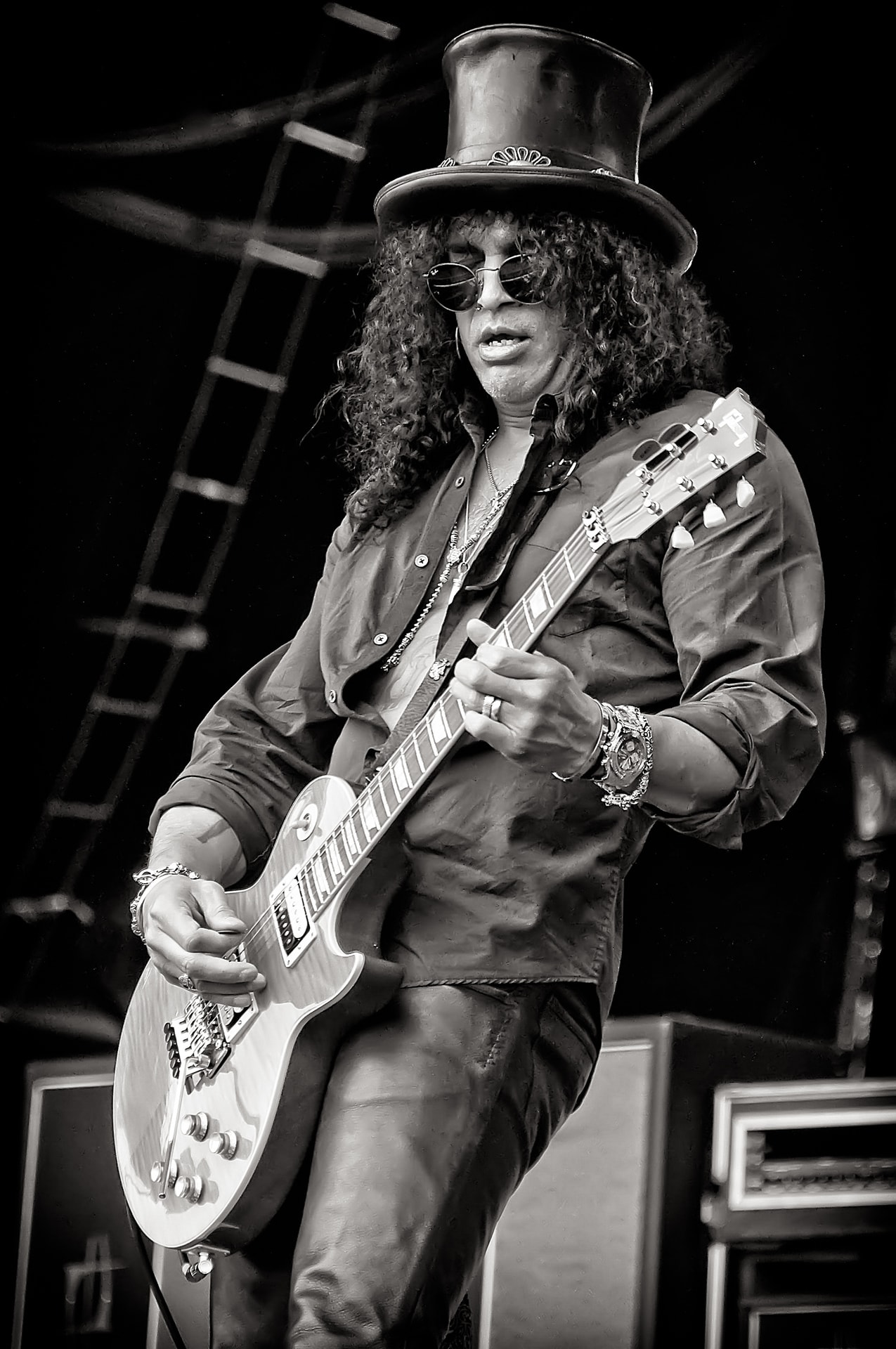 Slash performing live with an electric guitar in a black-and-white concert portrait
