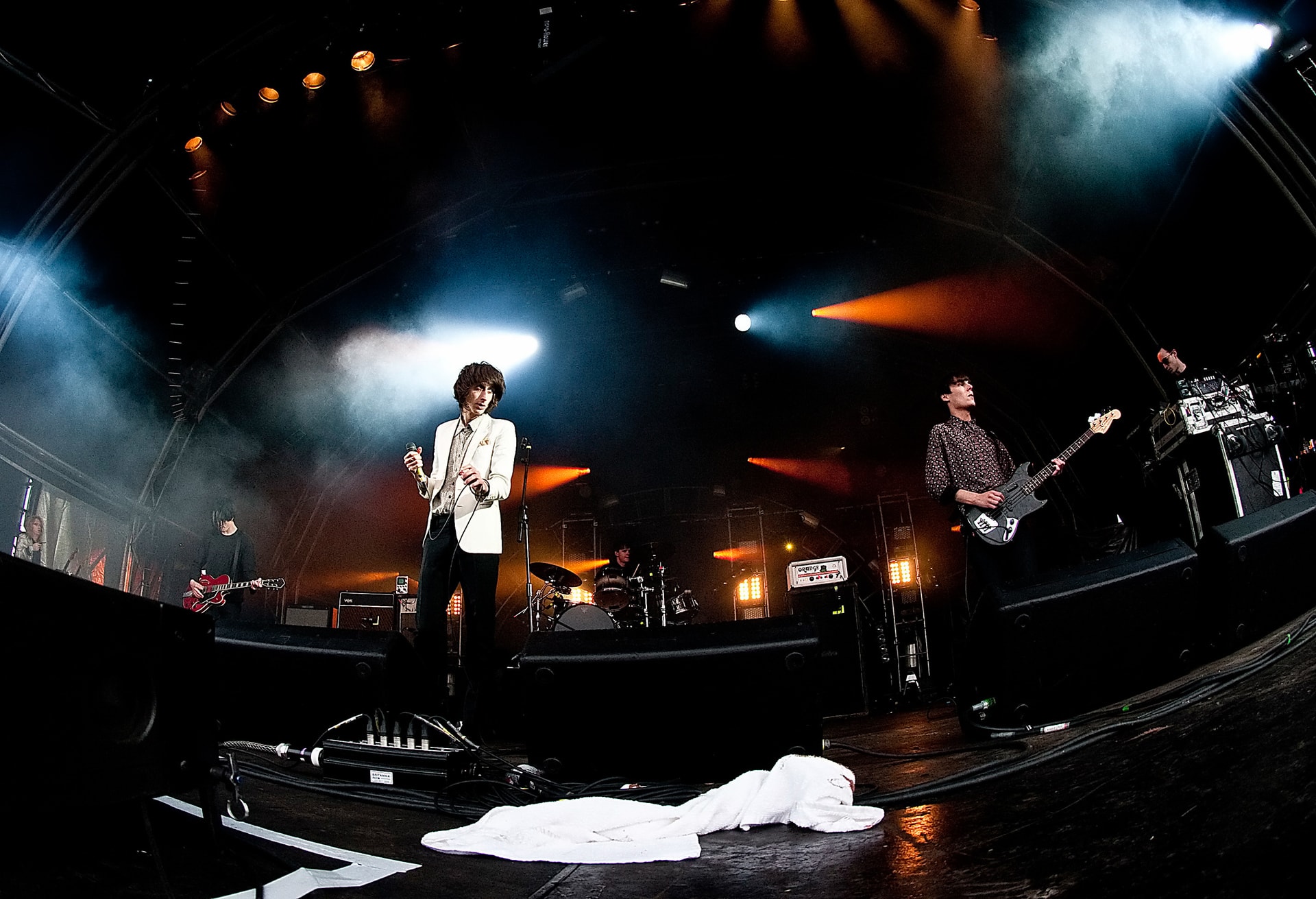 The Horrors performing on stage under blue, white and orange concert lights